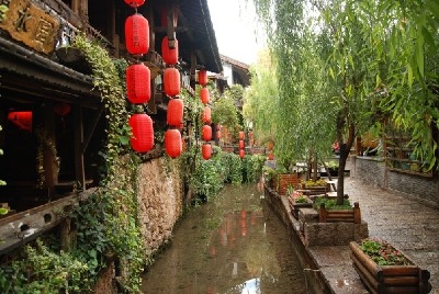 Chinese lanterns decorating, the architecture, along a walkway beside a waterway.